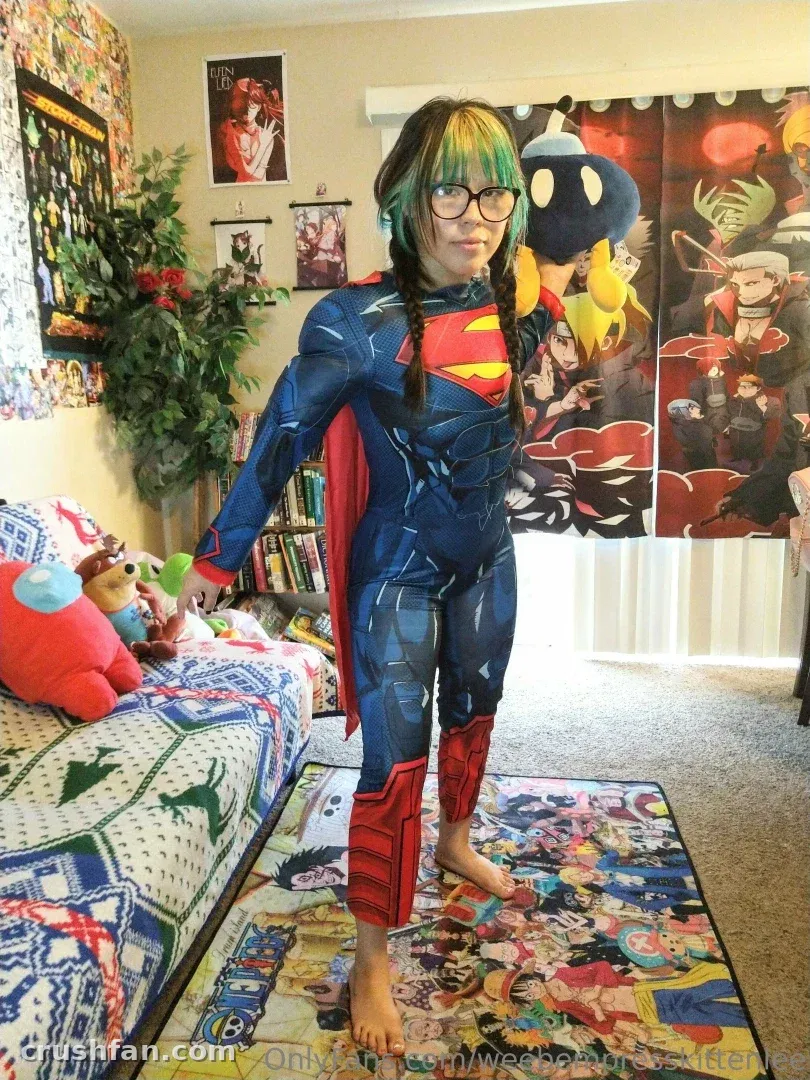 Créateur en costume de super-héros bleu, pieds nus dans une pièce colorée avec des affiches.