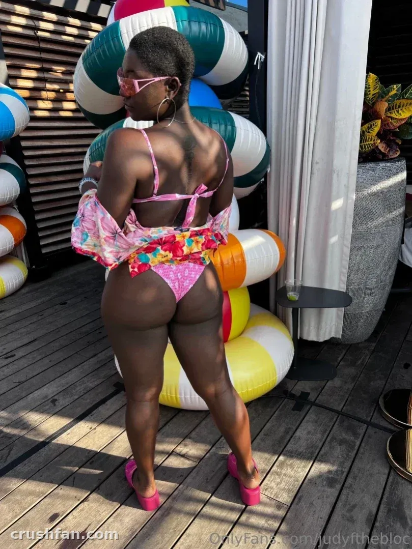 ItzJustJudy in a pink bikini standing on a deck with colourful inflatable rings