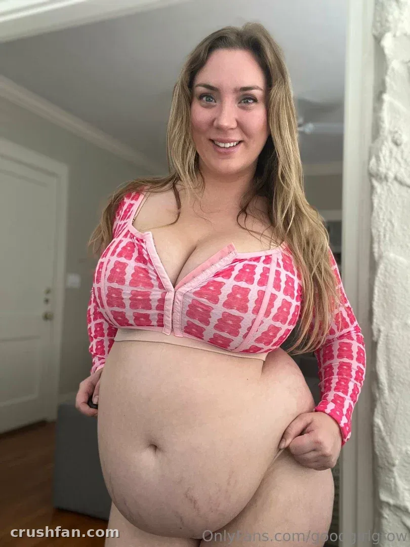goodgirlgrow lächelt in einem pinken gemusterten Crop-Top in einem Flur drinnen