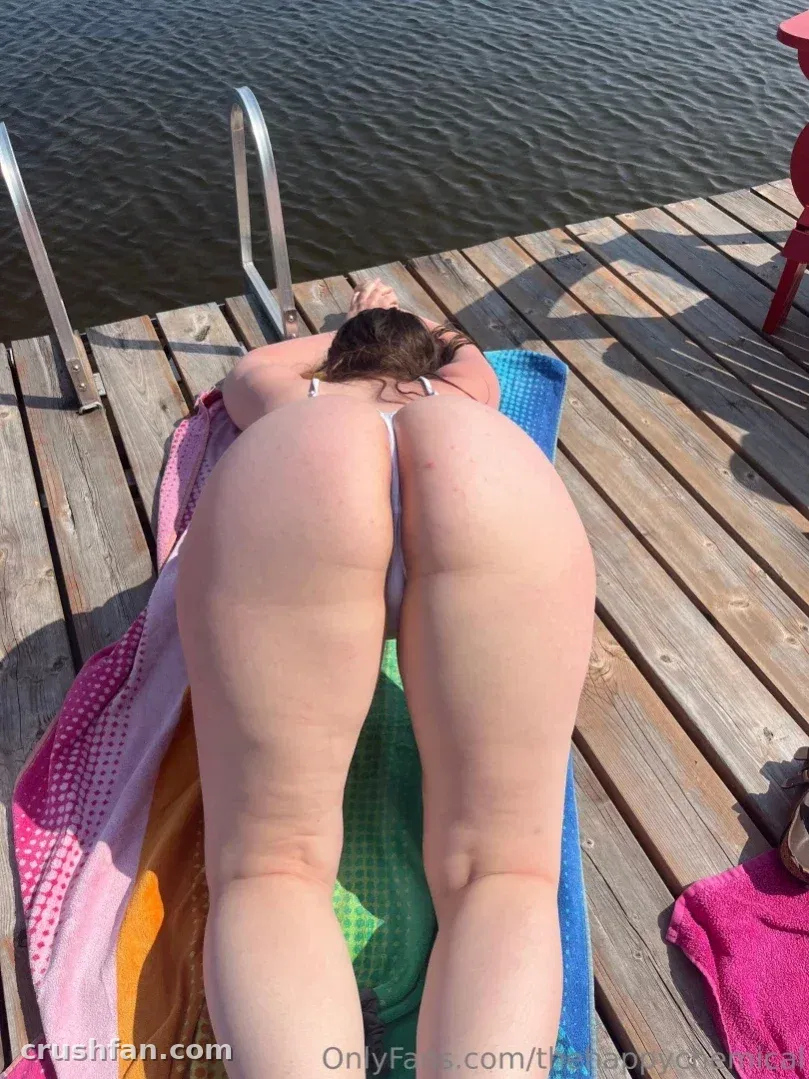Créateur allongé sur une serviette rayée sur un ponton en bois ensoleillé au bord de l'eau