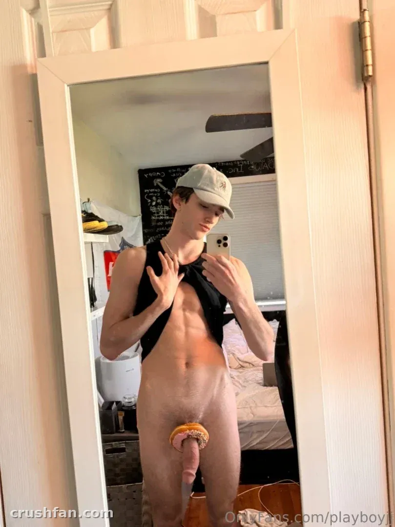 Jayden taking a mirror selfie in a cap and open shirt indoors