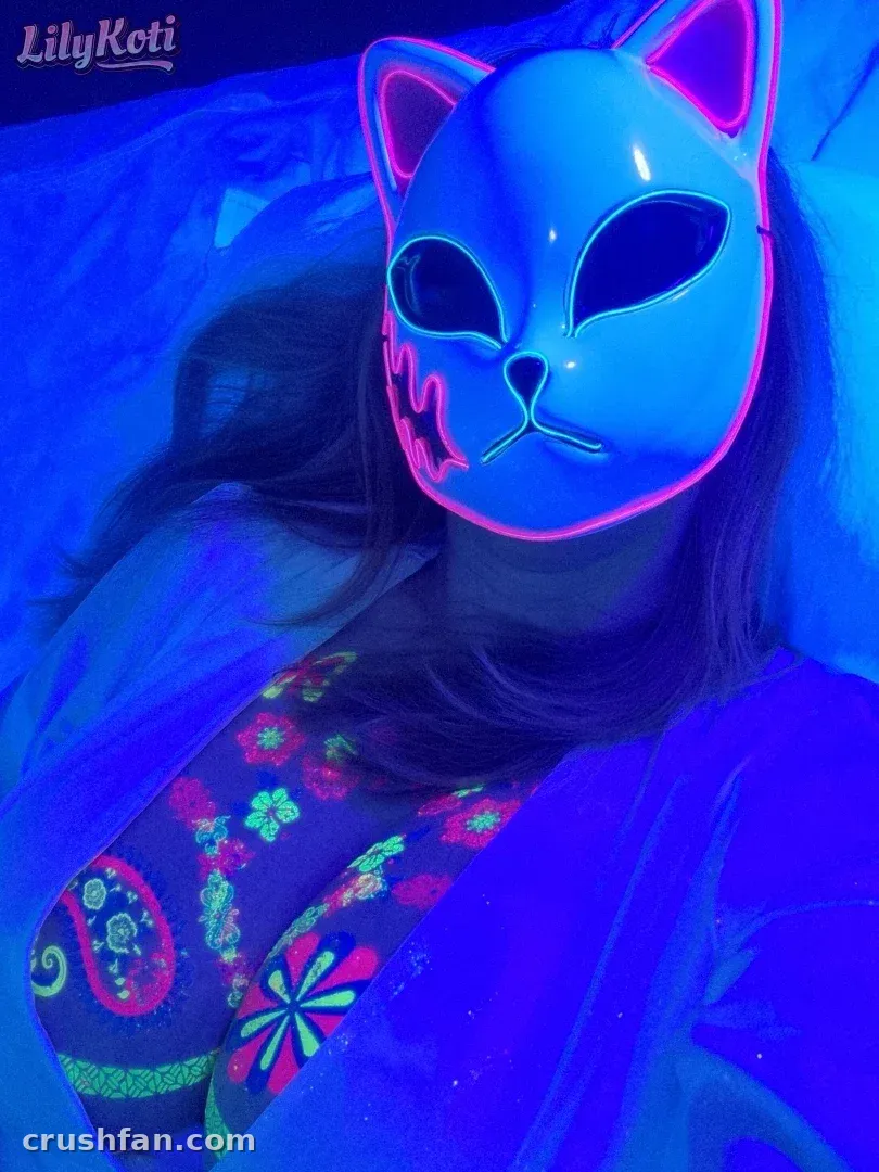 LilyKoti usando uma máscara de gato com contornos neon sob iluminação azul