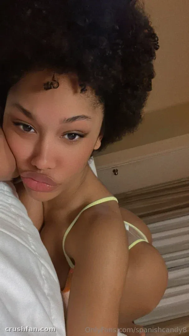Selfie en gros plan de Ms. ARii BANKS aux cheveux bouclés avec une moue espiègle contre un oreiller blanc.