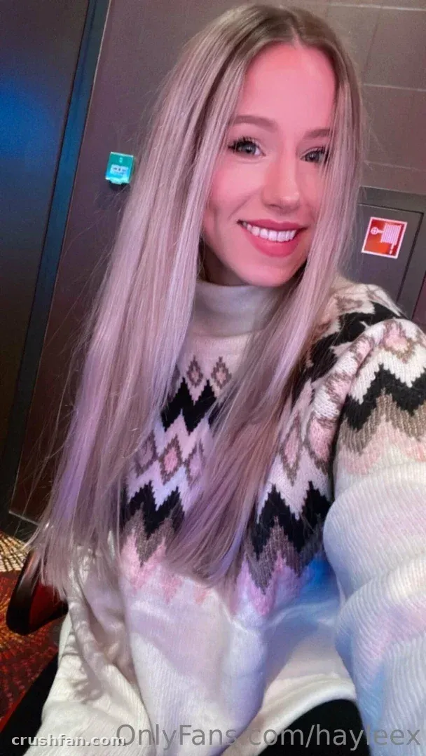 Hayleex sonriendo con un suéter de punto estampado blanco en una selfie en interiores