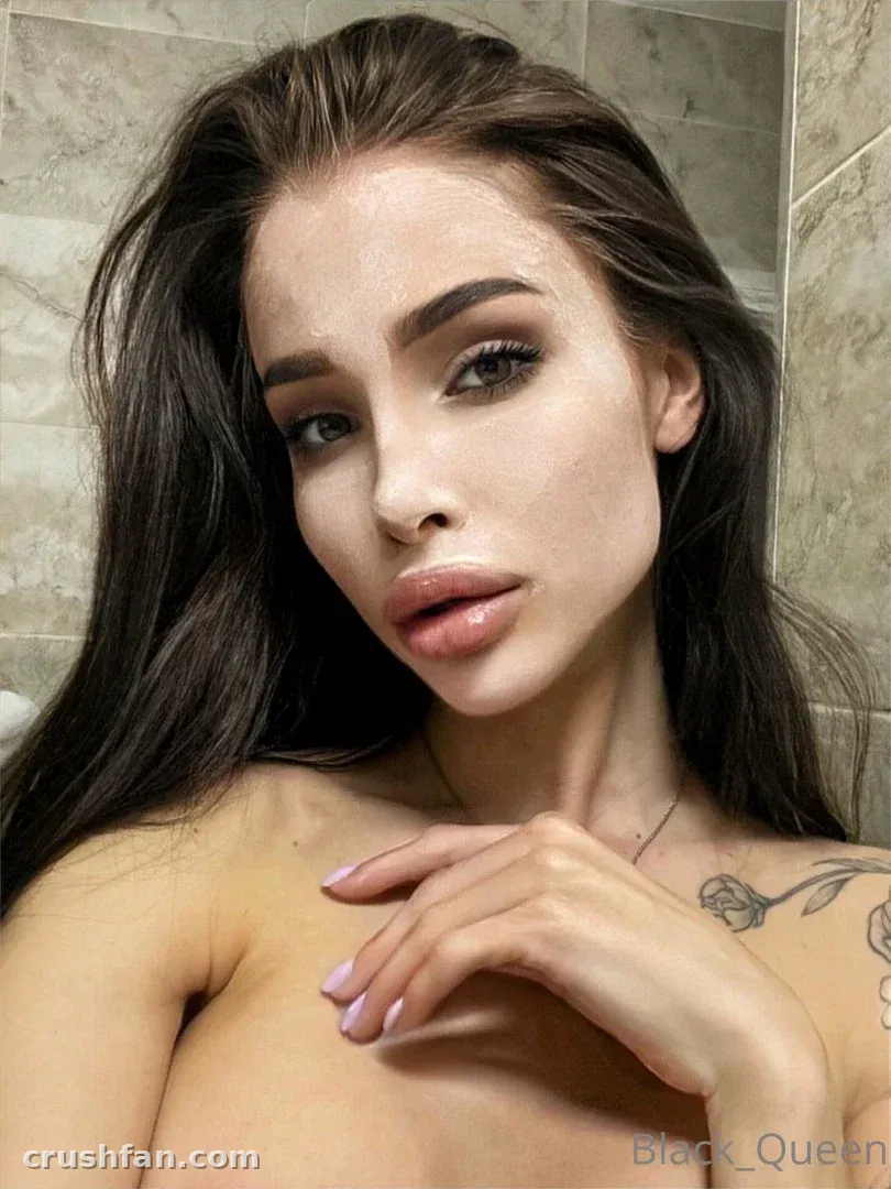 Darina con el pelo largo y oscuro posando en un baño con azulejos beige