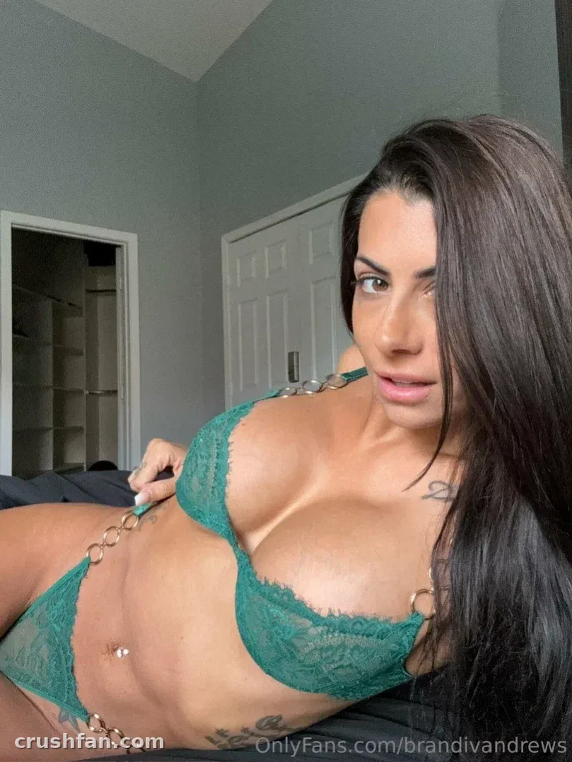Brandi Andrews in green lace lingerie reclining indoors against dark bedding