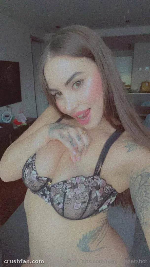 Creator in Blumenunterwäsche beim Indoor-Selfie mit sichtbaren Tattoos.