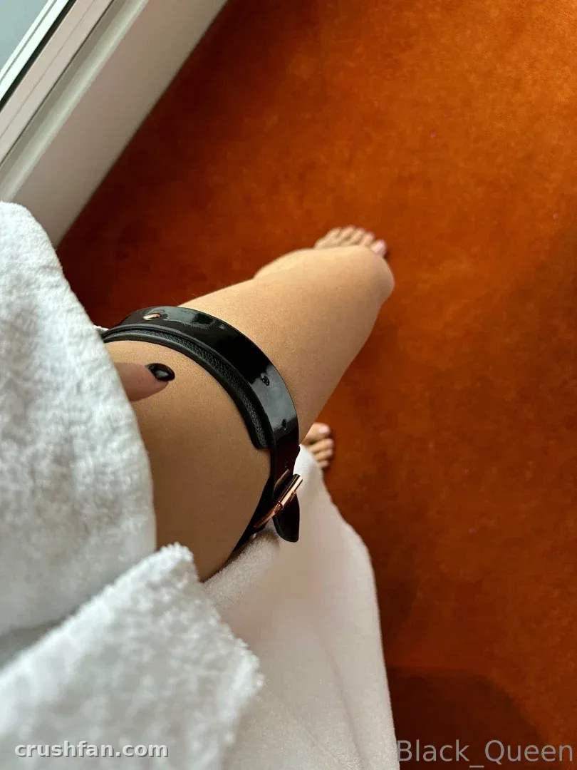 Darina Model from Ukraine wrapped in a white towel with a black strap around her leg, seated on an orange floor.