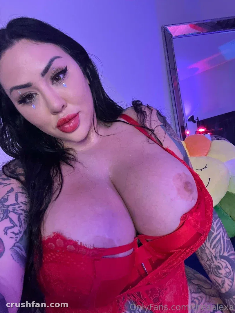 Drea Alexa in a red lace top taking a close-up selfie with purple lighting