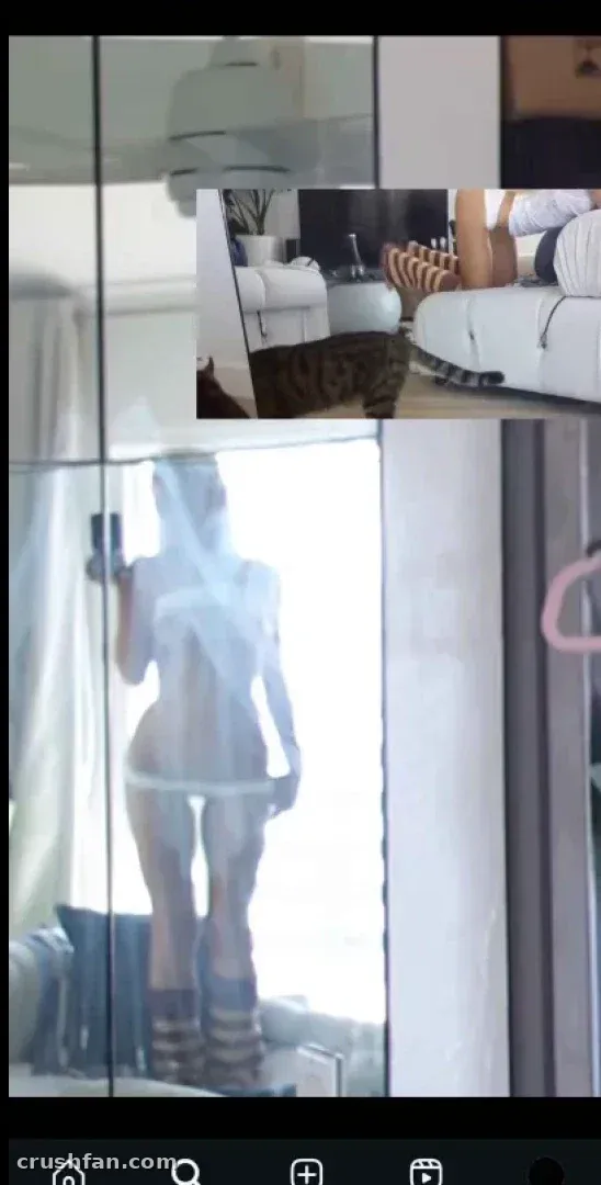 Kelly takes a mirror selfie in a bright indoor room with neutral tones.
