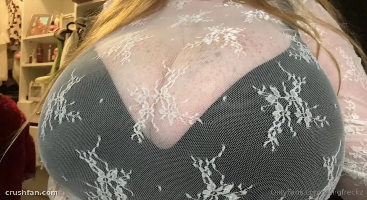 Missy dans un haut en dentelle grise transparente avec de longs cheveux blonds dans une pièce à l'éclairage doux