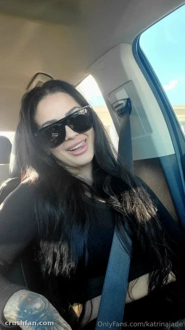 Katrina Jade em um carro usando óculos escuros e uma blusa preta.