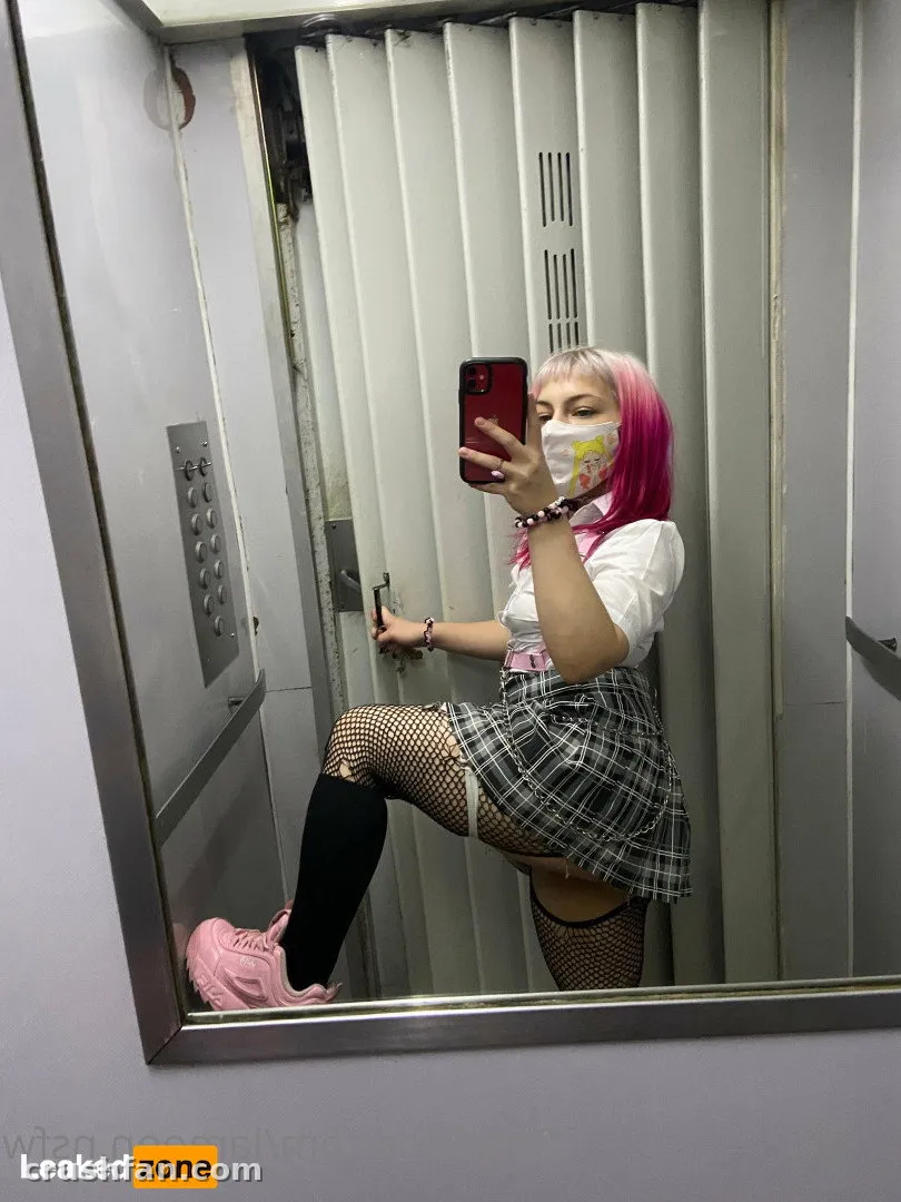 Selfie no espelho em um elevador mostrando uma criadora com saia xadrez, meia-calça e tênis rosa