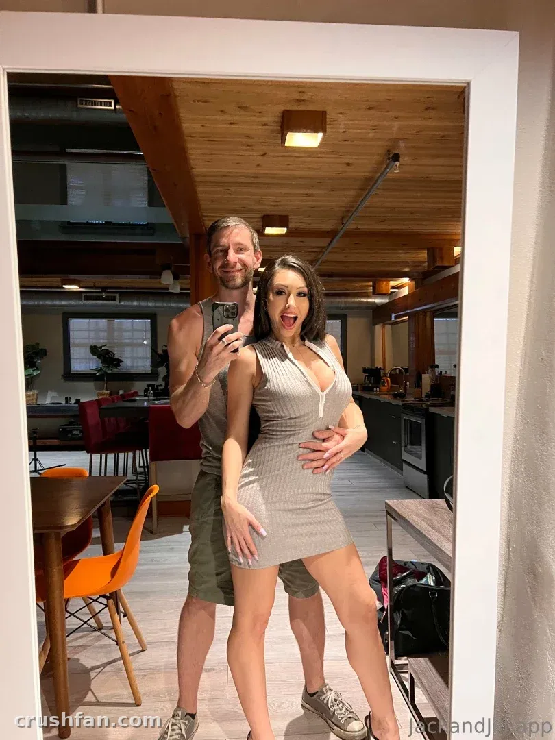Creator in a grey striped dress taking a mirror selfie in a room with wooden ceiling and orange chairs.
