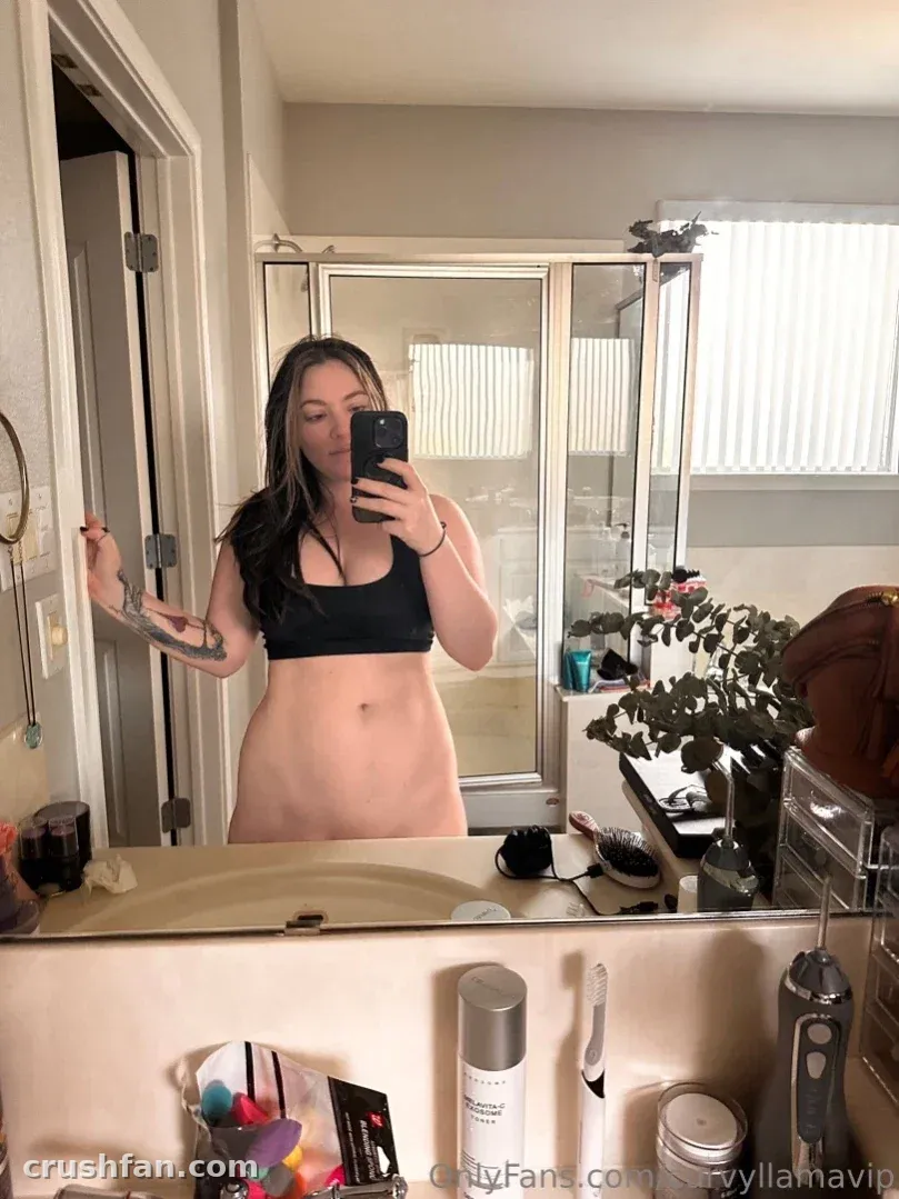 Creatorin in einem schwarzen Crop-Top macht ein Spiegel-Selfie in einem hellen Badezimmer