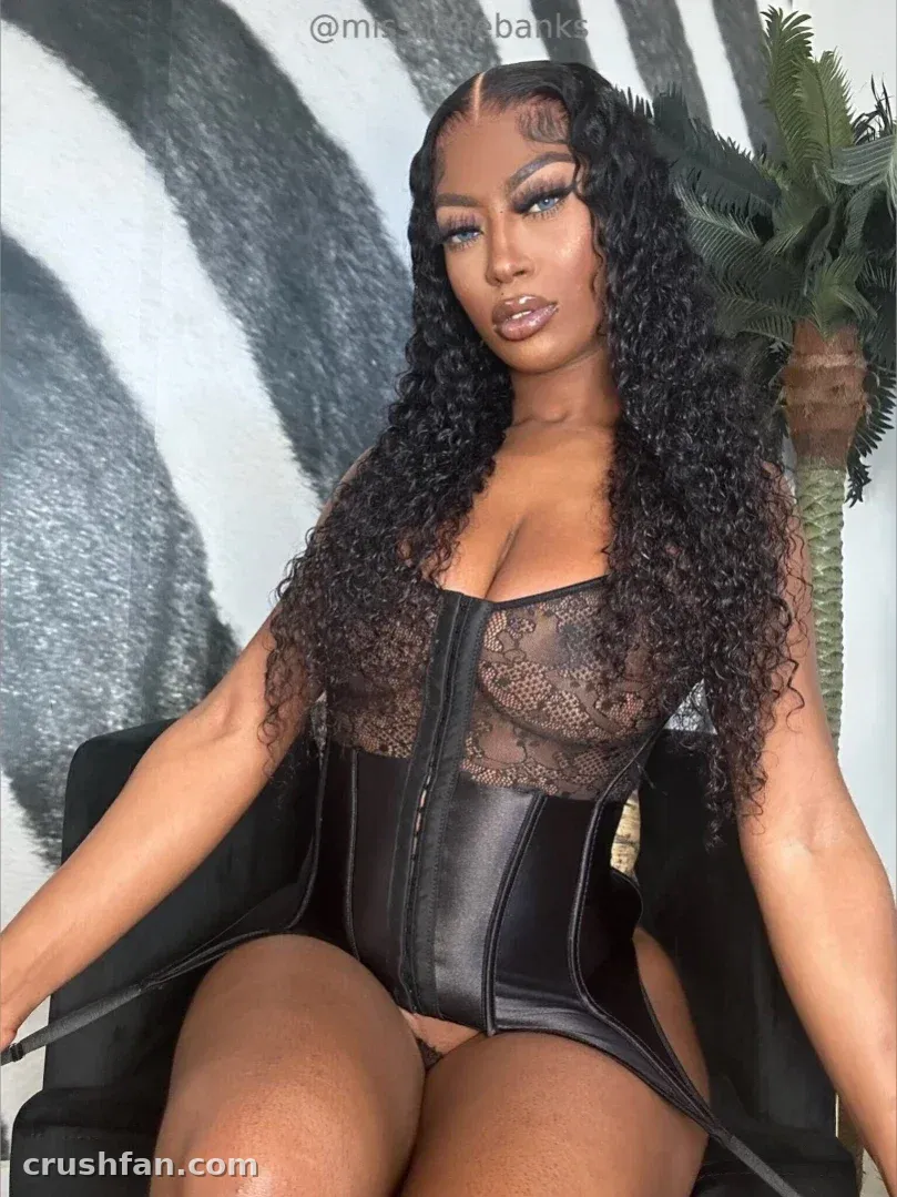 Miss Nene Banks sentada em um espartilho de renda preta e couro contra um fundo em preto e branco