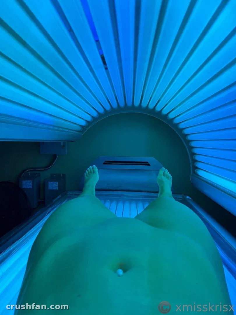 View from inside a tanning bed showing blue lights and a person lying down.