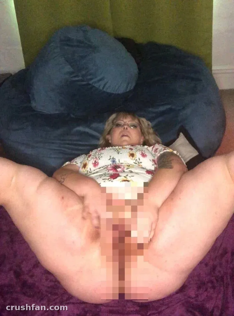 McJigglezzz reclining on a blue beanbag chair in a floral top with a purple blanket in the foreground.