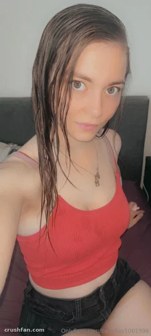 Creator Babykay in a red crop top and dark shorts indoors, looking at the camera.