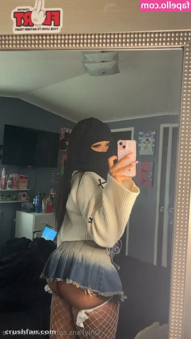 h o n e y in a cream knit and denim skirt taking a mirror selfie in a dim room