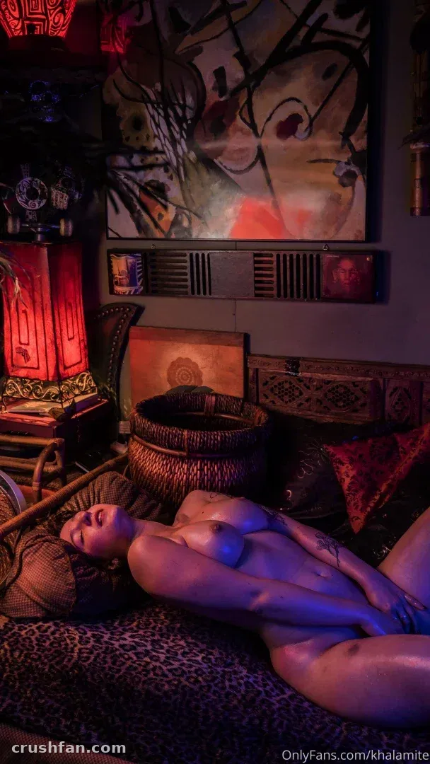 Khalamité recostada en una habitación con luz cálida, arte abstracto y lámpara roja