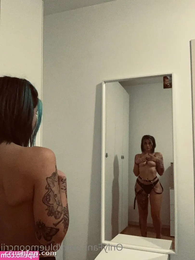 BlueMoonCrii tomándose una selfie en el espejo con lencería oscura, tatuaje visible en el brazo