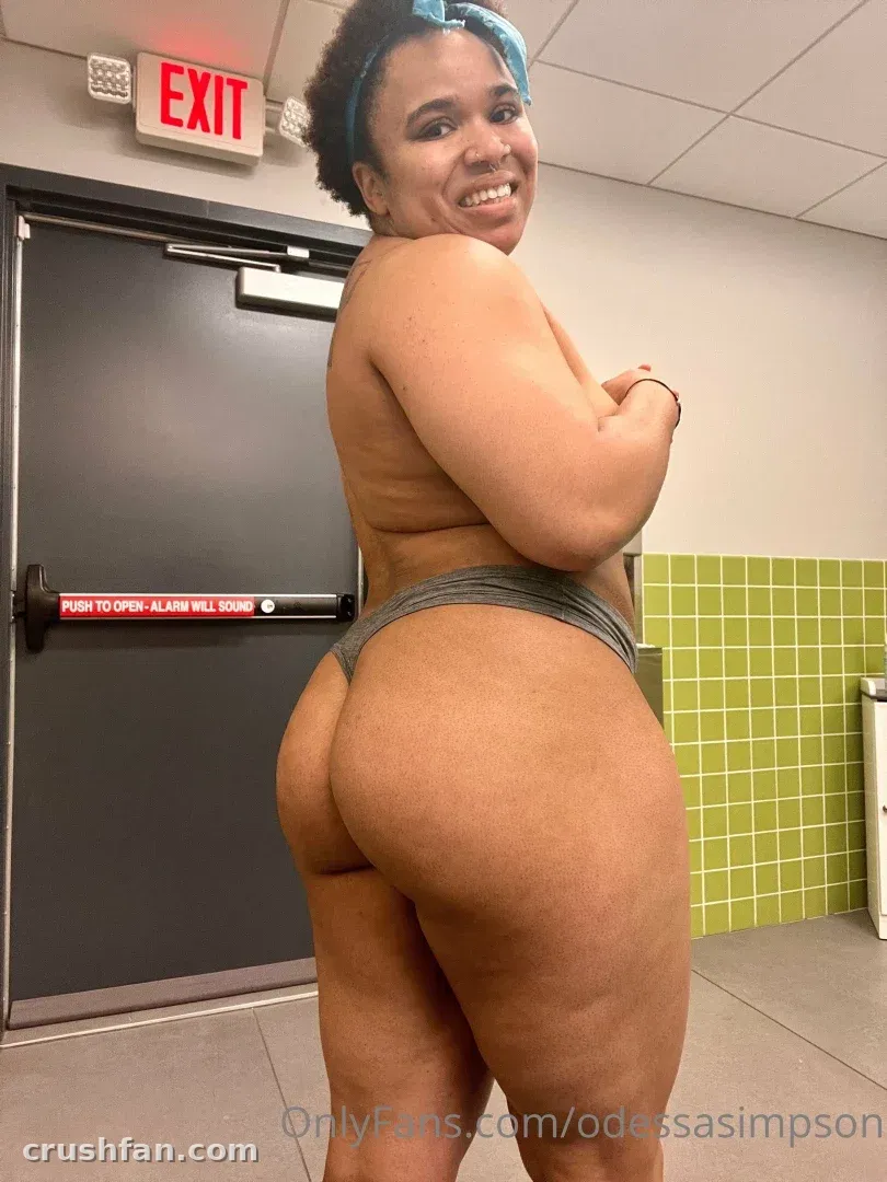 Creator com faixa azul e bottom cinza sorrindo em um corredor de academia com azulejos verdes.