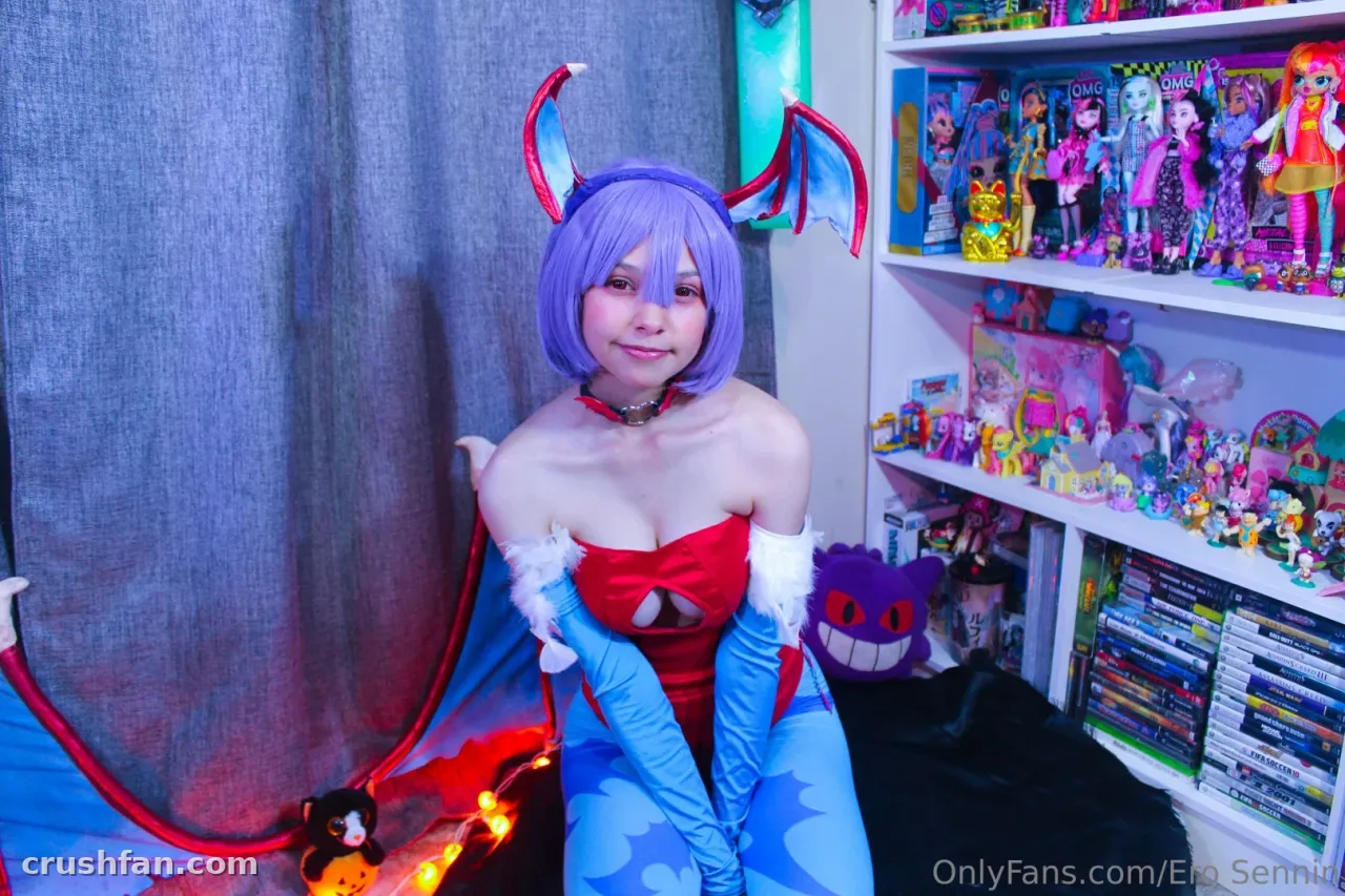 Rin Cosplay con una peluca morada y un traje de cosplay rojo sentada en interiores junto a estanterías con juguetes.