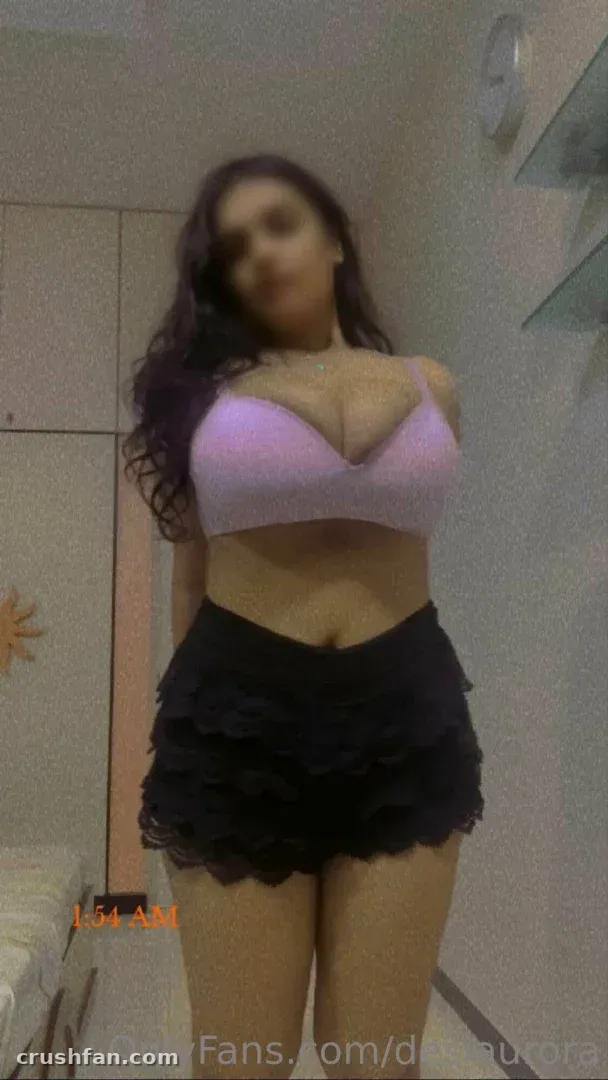 Desi Aurora in a lilac bralette and black ruffled shorts standing indoors