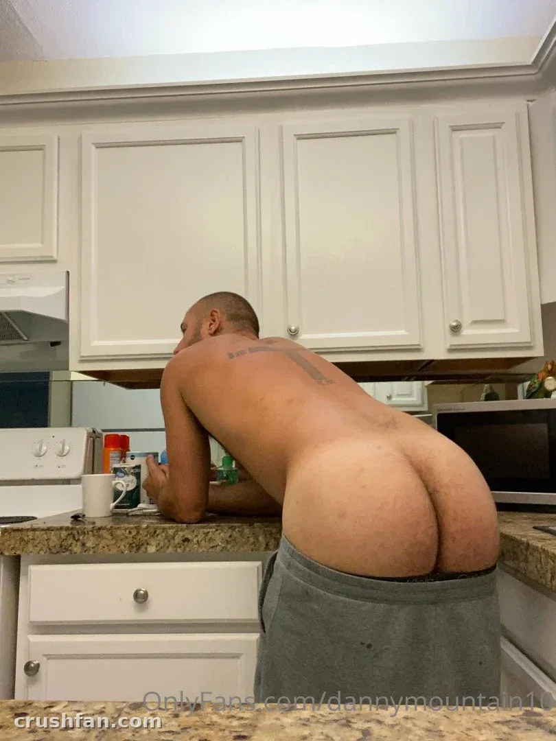 Danny Mountain inclinando-se sobre uma bancada de cozinha em calça de moletom cinza
