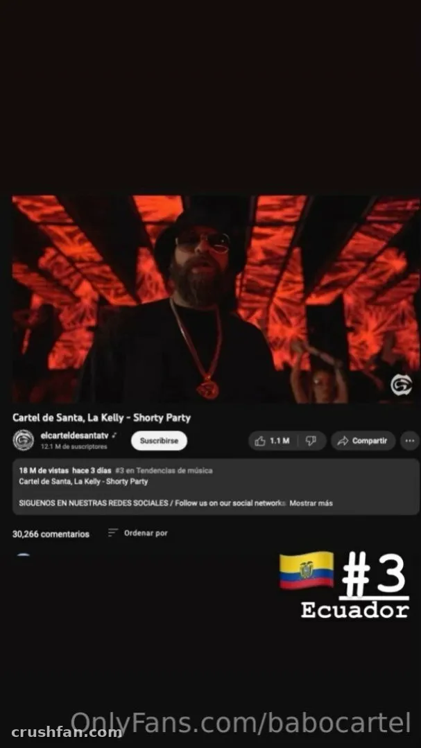 Babo Cartel de Santa dans une scène de clip musical rouge foncé avec casquette noire et pendentif.