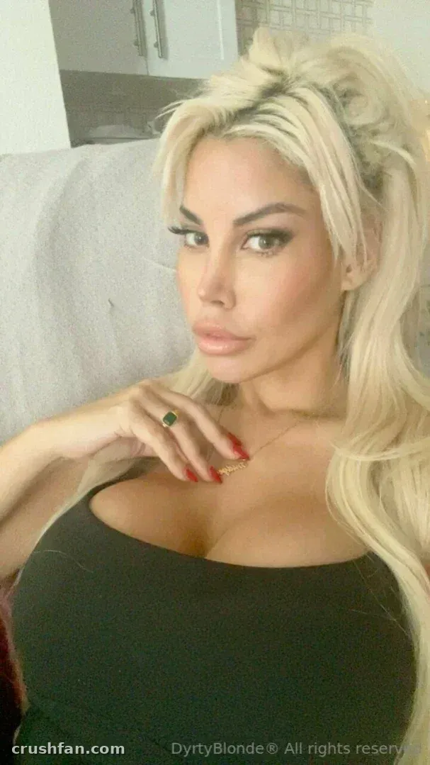 Bridgette B com um top preto e cabelo longo loiro em um rabo de cavalo alto.