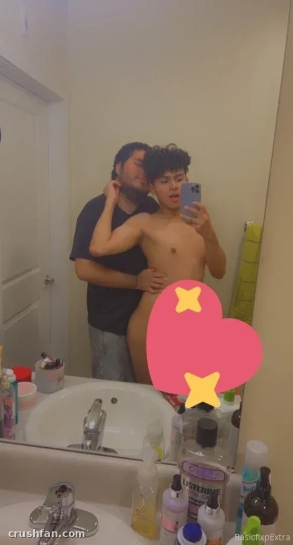 Extra Content taking a mirror selfie in a bathroom with a pink heart sticker.