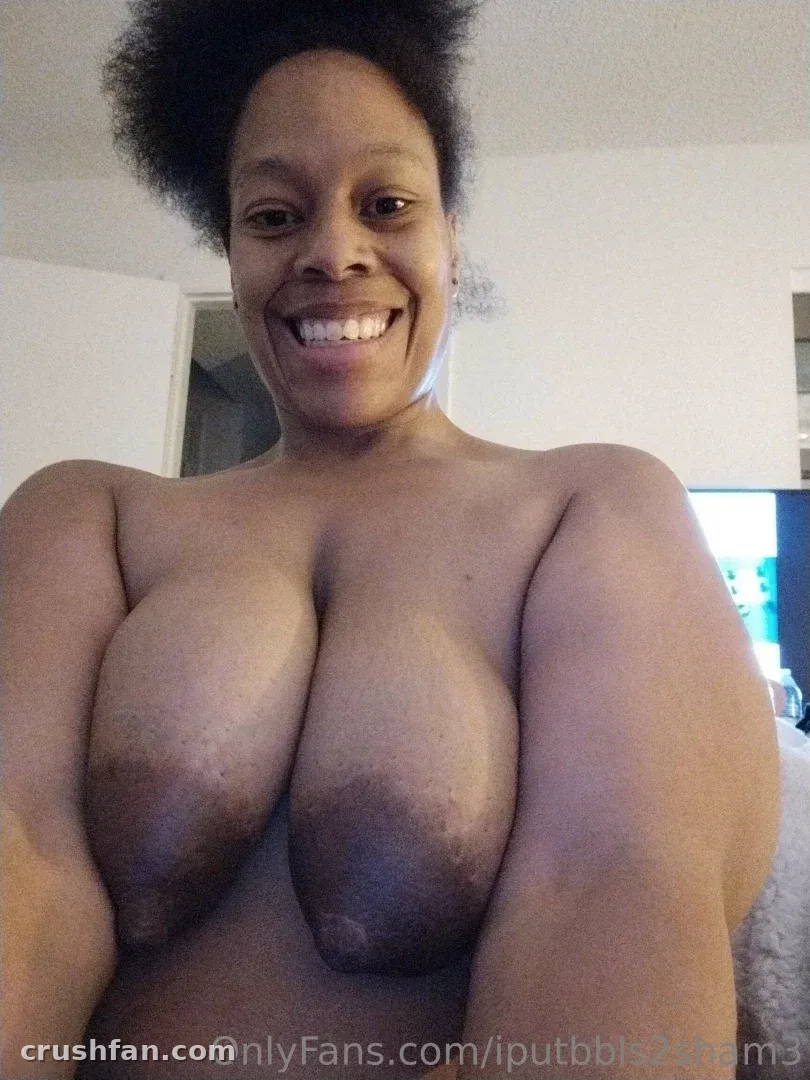 Femme souriante aux cheveux foncés dans un selfie en gros plan en intérieur devant un mur uni