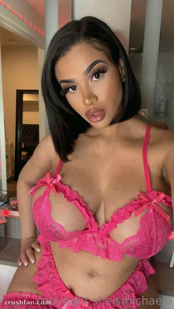 Michaela in pink ruffled lingerie posing indoors in a softly lit room