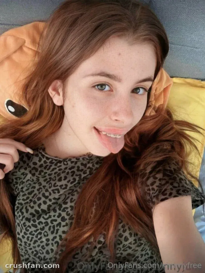 Kimmy Monroe in a leopard print top lying on orange cushions in a close-up selfie