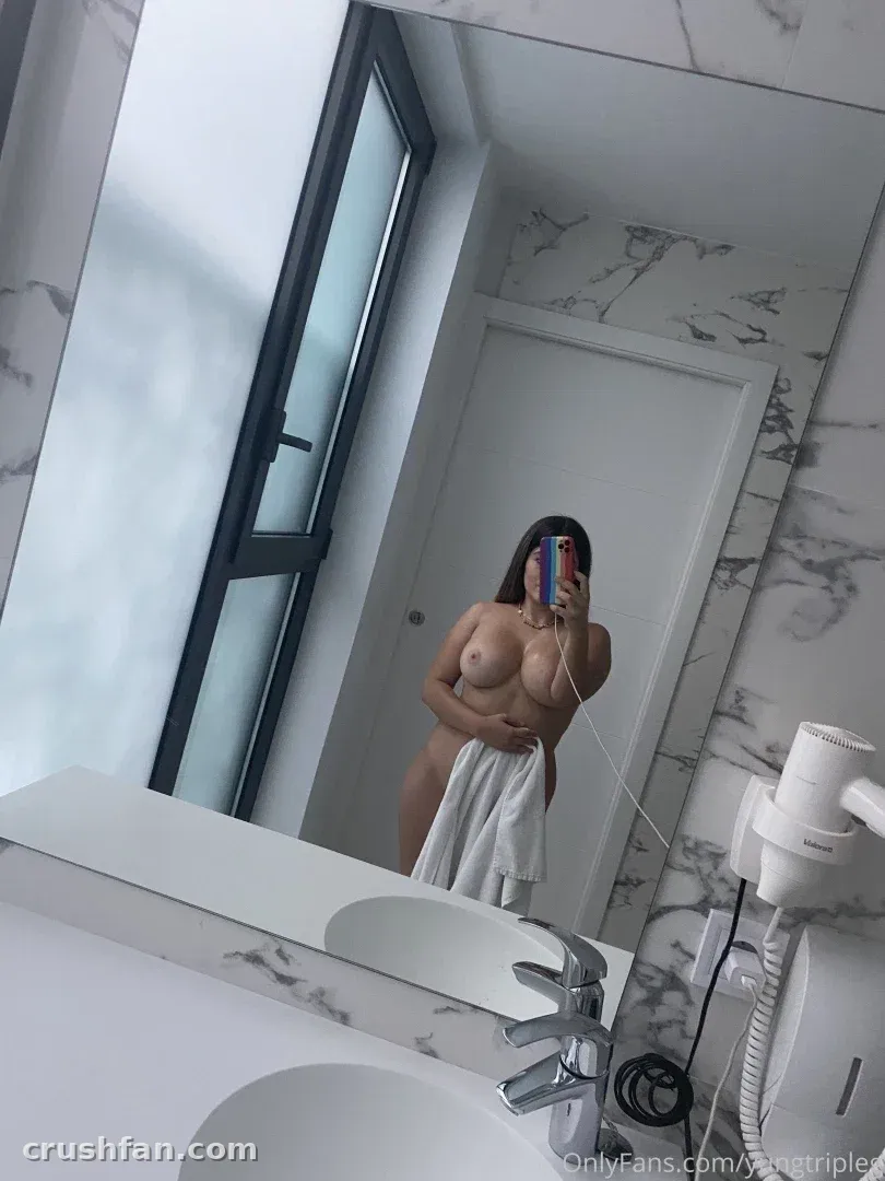 Gema takes a mirror selfie in a marble bathroom while holding a towel