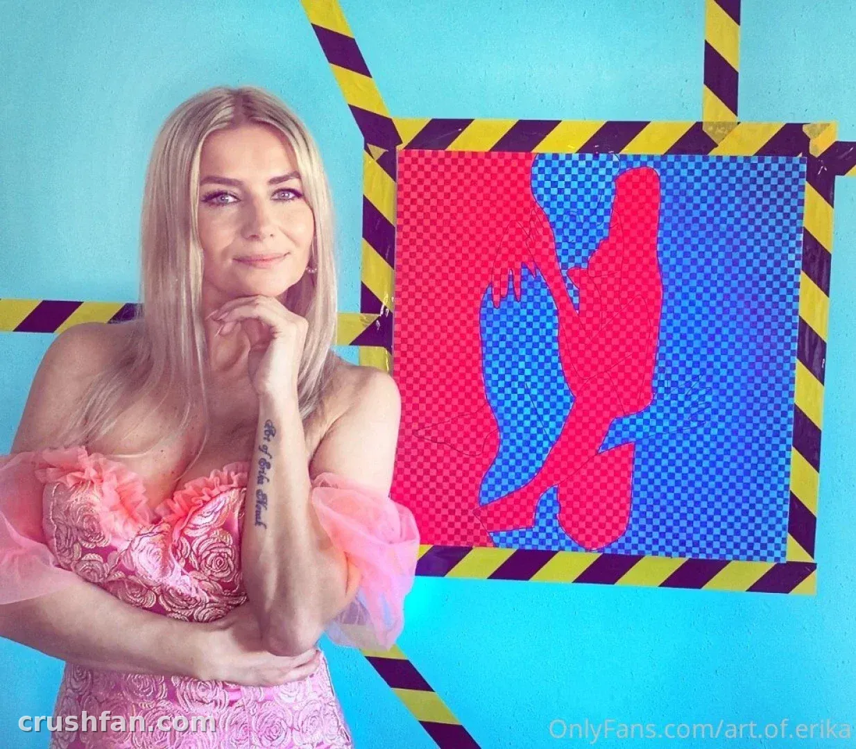 Bad Ery in a pink lace top posing in front of a colourful pop art canvas