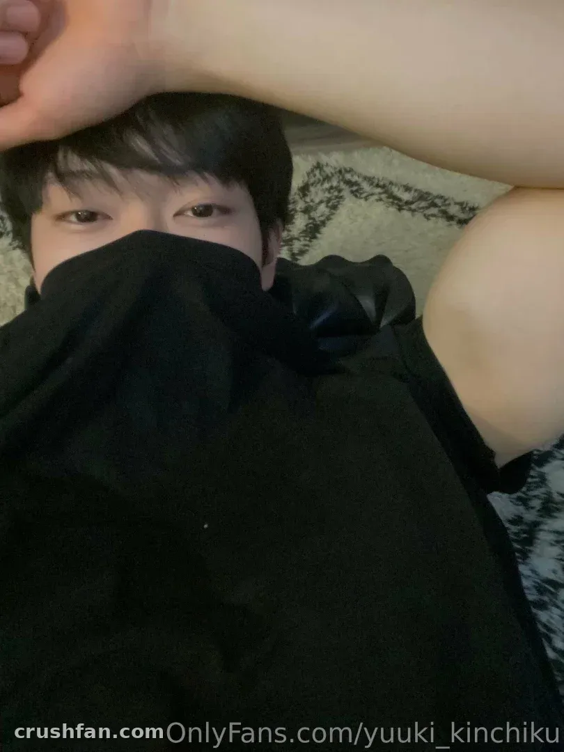Yuuki lying on a patterned bed with her arm raised and black fabric covering her lower face