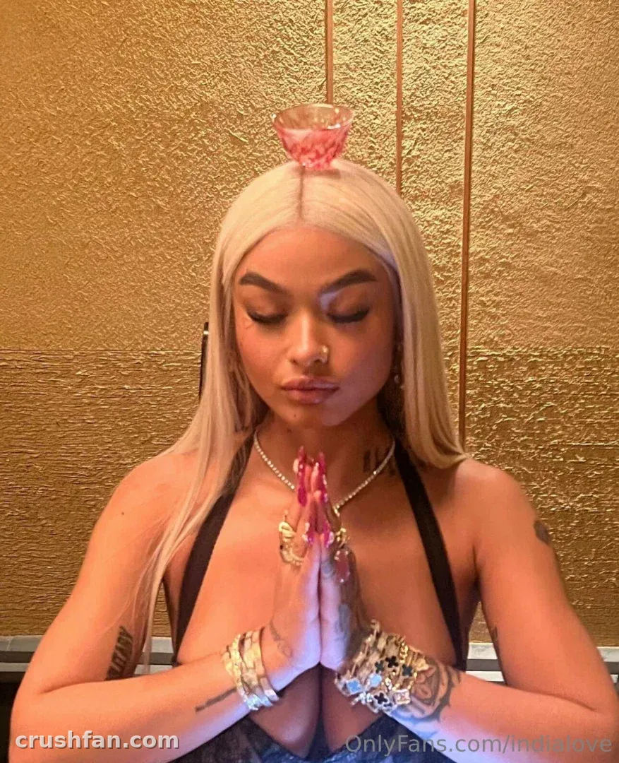 India Love com os olhos fechados e as mãos juntas, um pequeno recipiente rosa equilibrado na cabeça