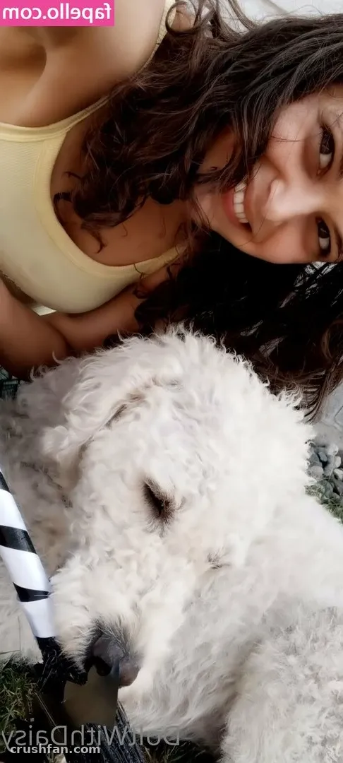 DoItWithDaisy in a yellow top smiling next to a fluffy white dog