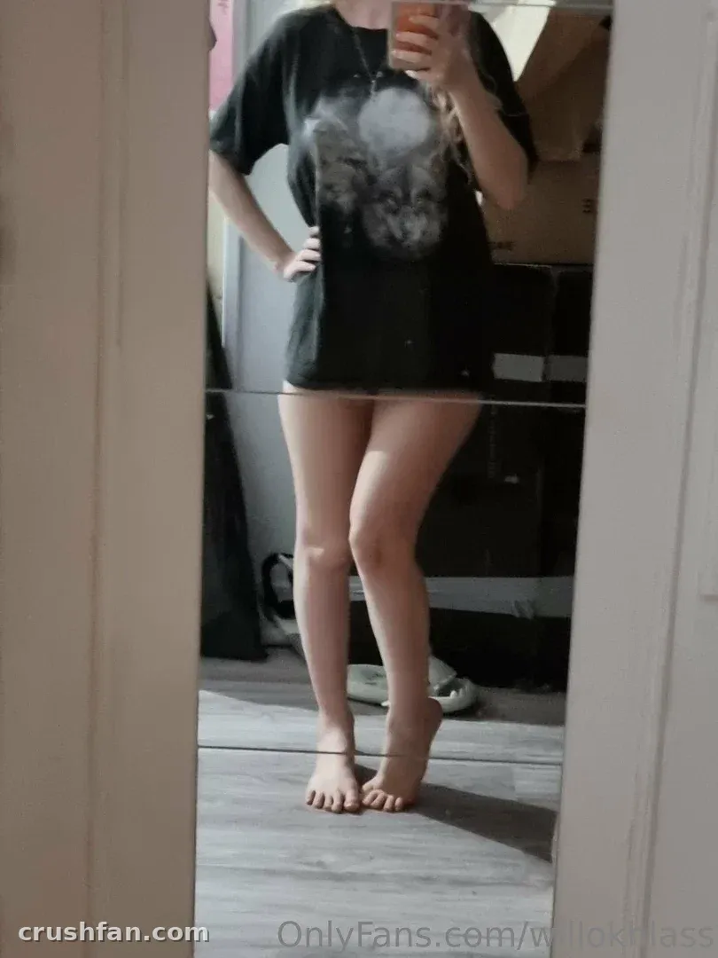 Willokhlass in an oversized black graphic t-shirt taking a mirror selfie in a pale room