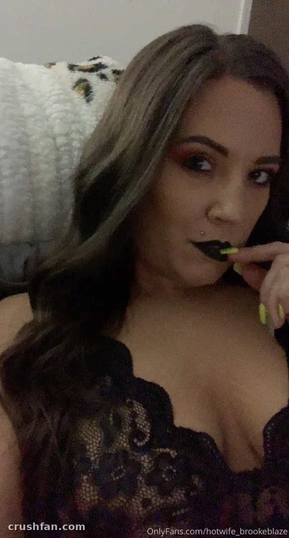 Femme en haut en dentelle noire avec un maquillage audacieux se touchant les lèvres à l'intérieur