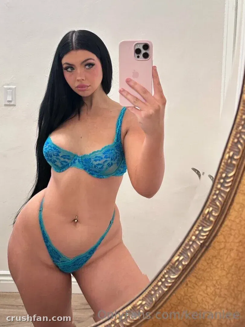 Woman in blue lace lingerie taking a mirror selfie with a pink phone