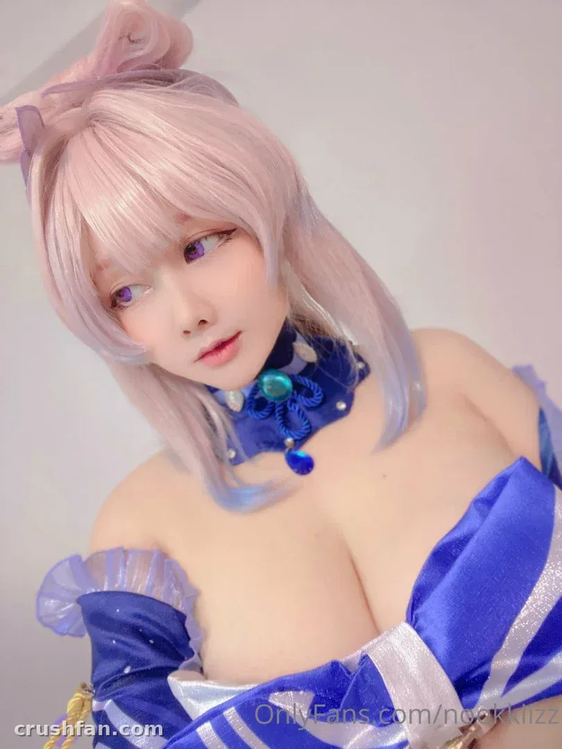 NookkizzCos in a blue and silver cosplay with pastel pink hair against a light wall