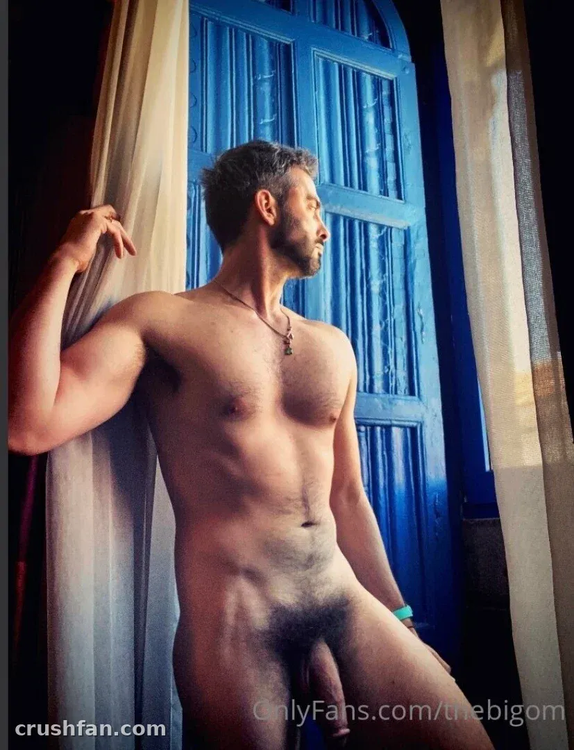 The Big 'Om' with Kae standing by a blue door and sheer curtain in warm light.
