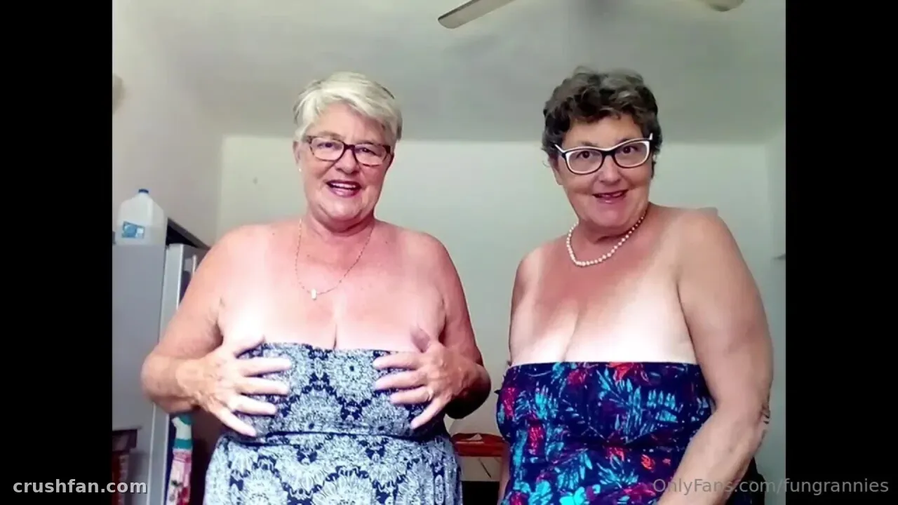 Two women with glasses smiling indoors in a bright room with patterned clothing