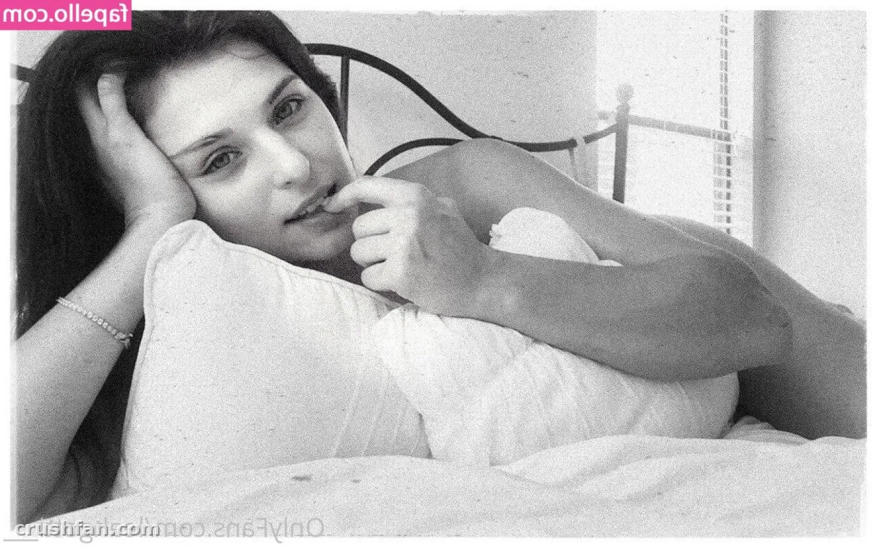 Retrato em preto e branco de uma mulher descansando em uma cama com um travesseiro branco
