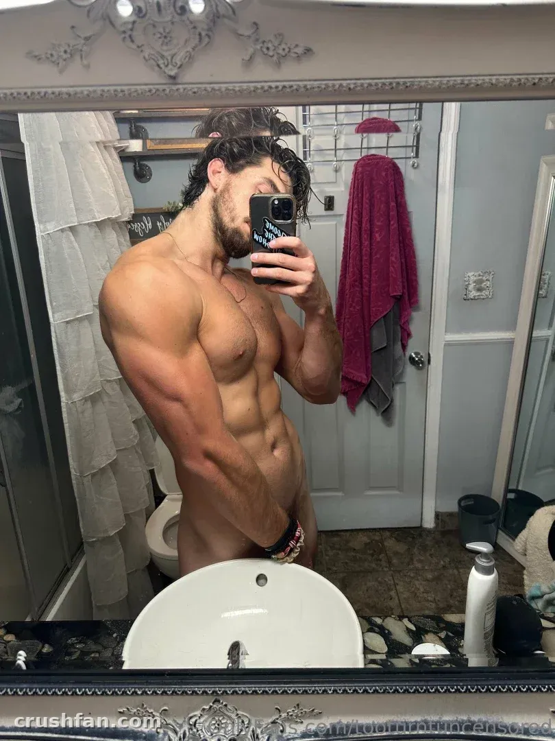 Too Turnt Tony prend un selfie miroir torse nu dans une salle de bain avec une serviette rose derrière lui.