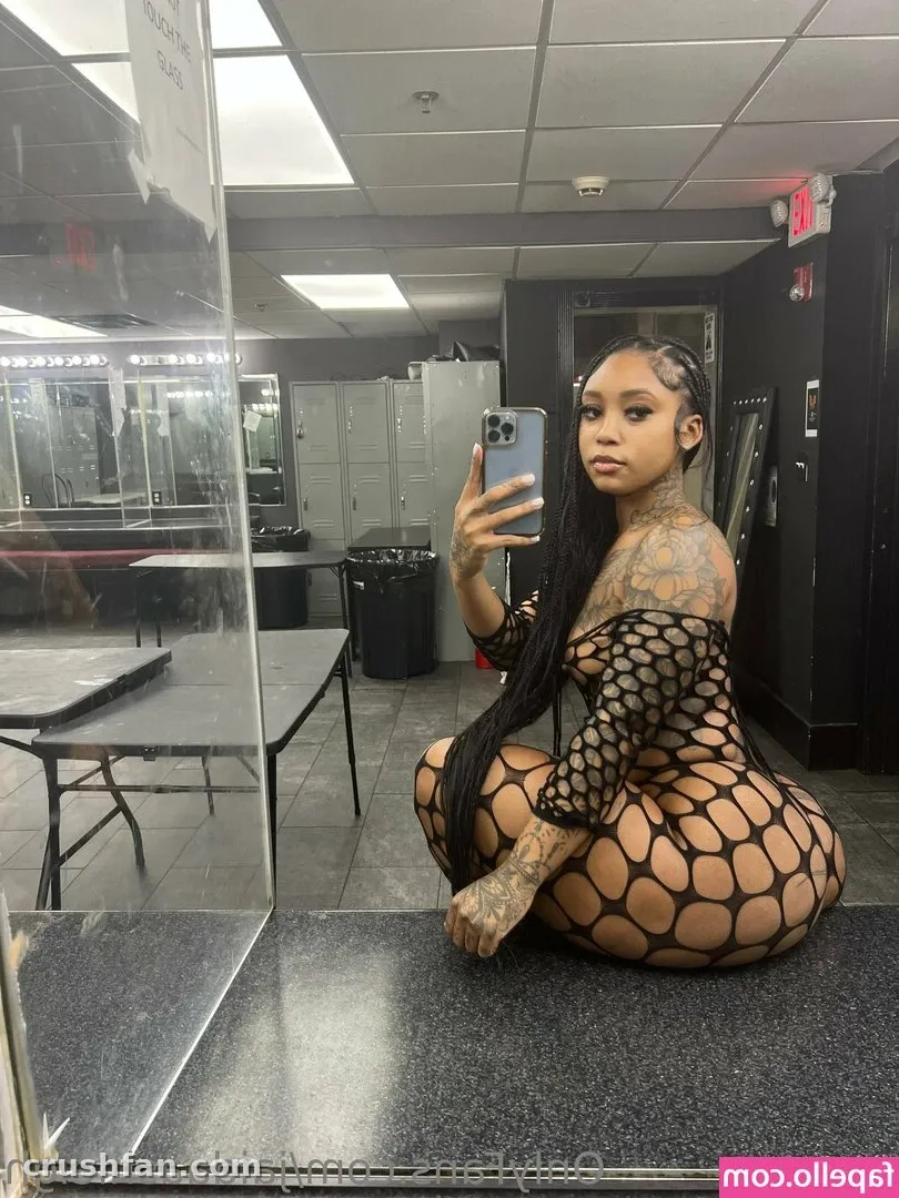 Creator in a black honeycomb fishnet bodysuit taking a mirror selfie in a dressing room.